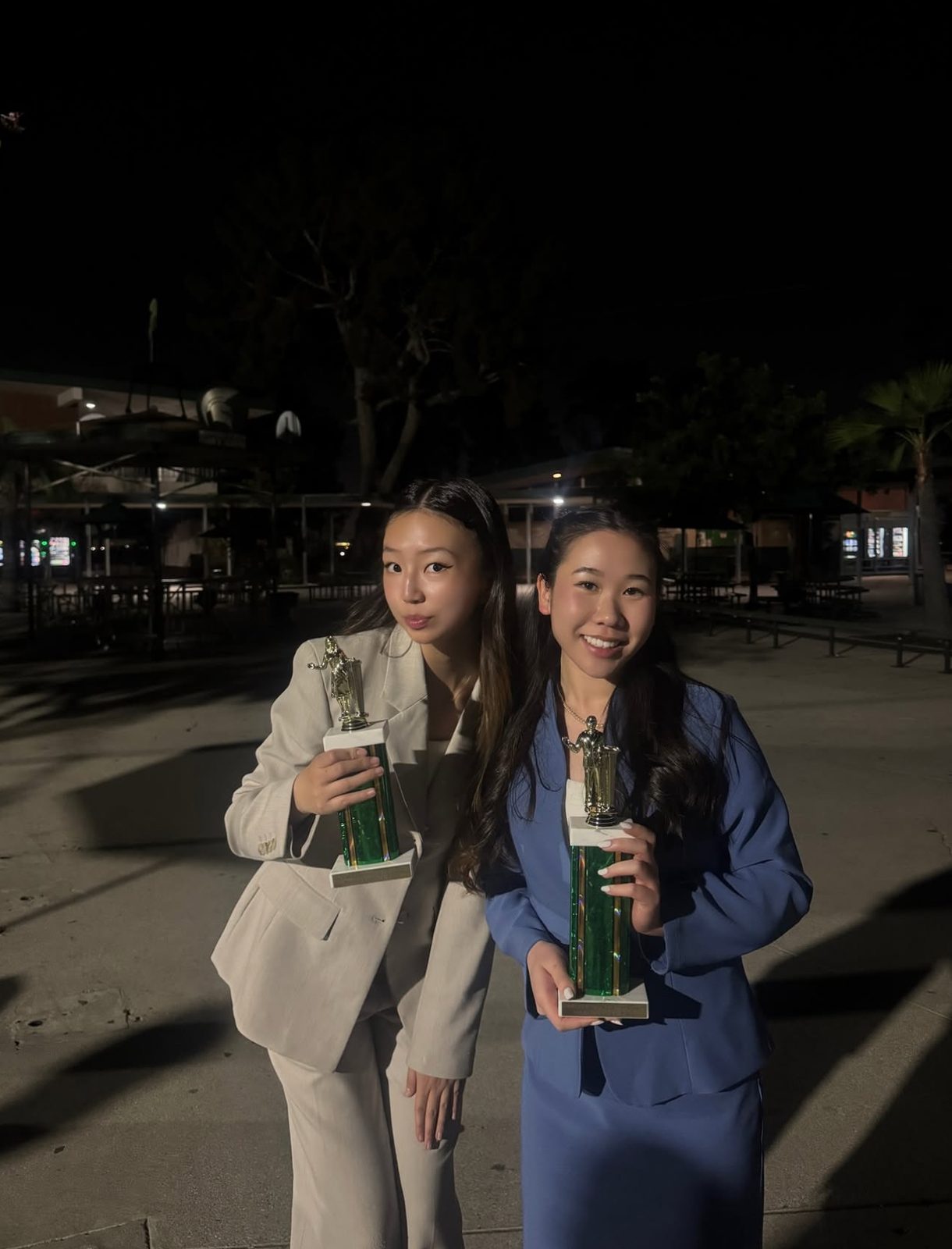Two competitors with trophies outside at night