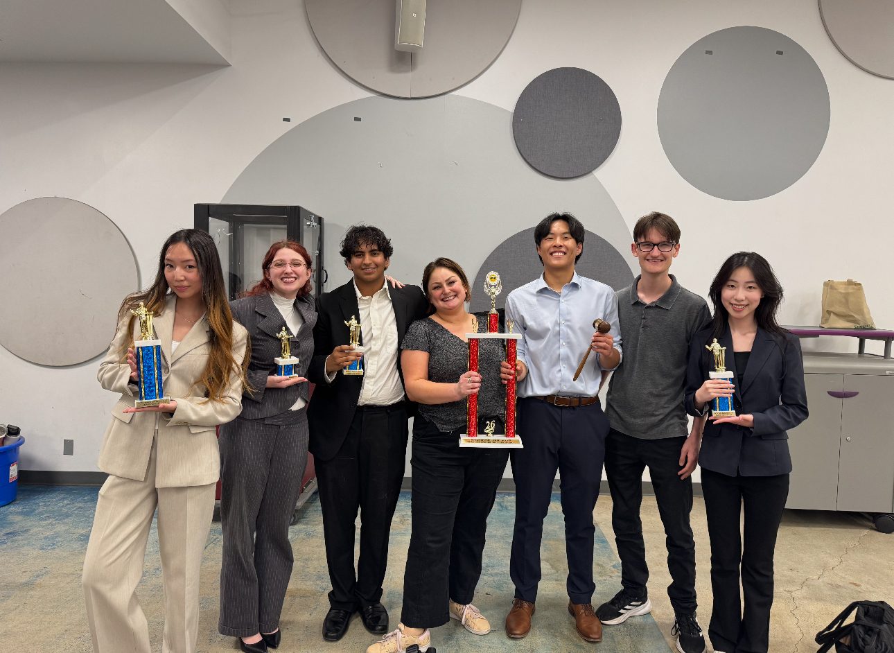 A team of six holding trophies in a classroom