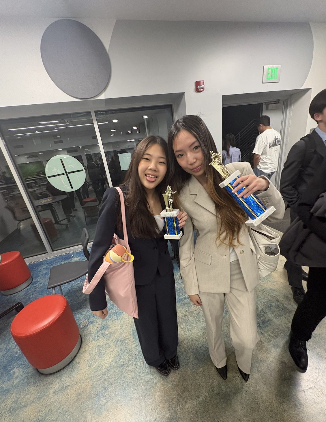 Two competitors with a trophy in a hallway