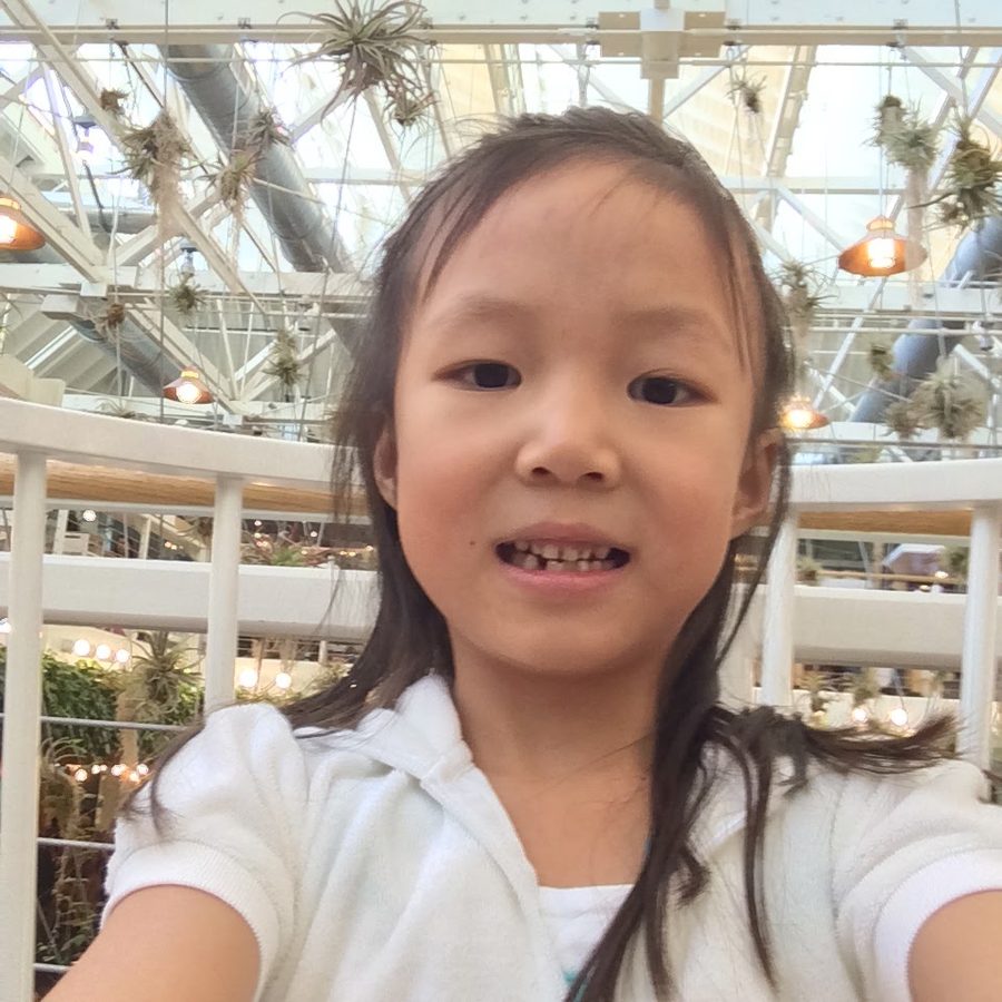 A young girl holding the camera at arm’s length, grinning