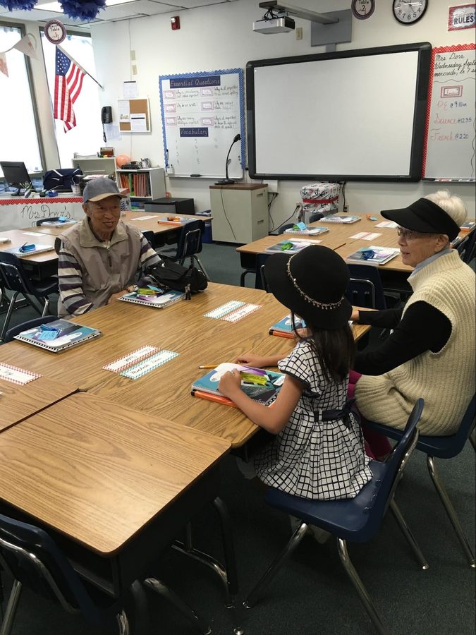 A classroom table of second graders and visiting grandparents