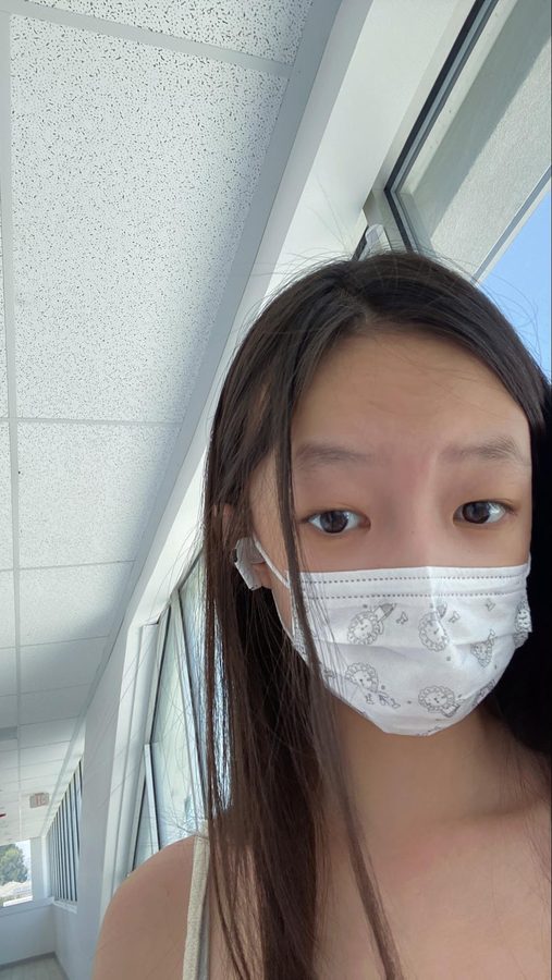 A masked selfie taken by a window on the first day of lockdown